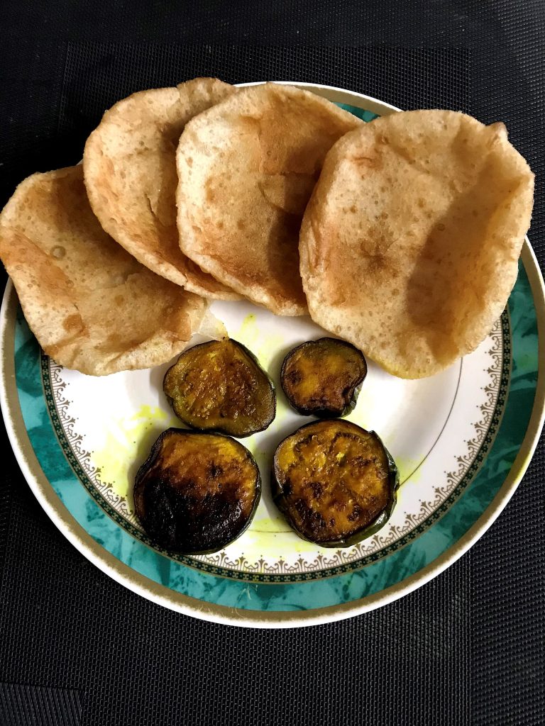 Luchi served with begun bhaja, a traditional Bengali breakfast platter