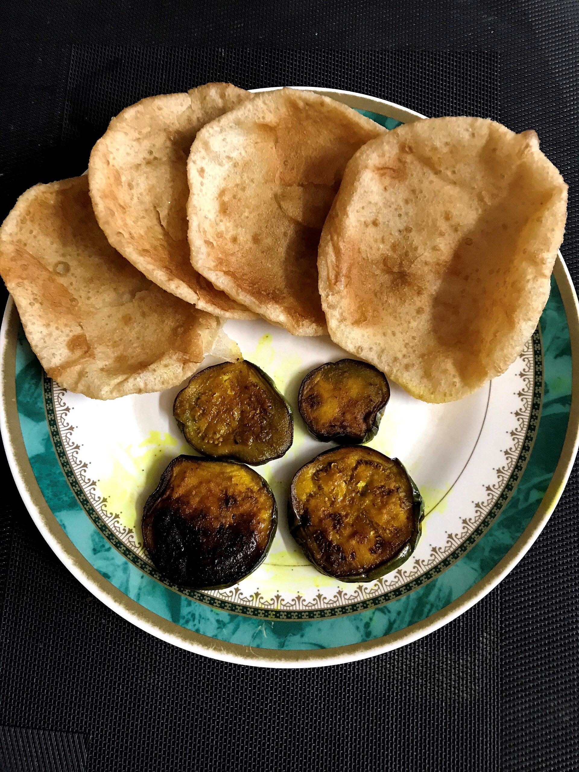 Luchi served with begun bhaja, a traditional Bengali breakfast platter